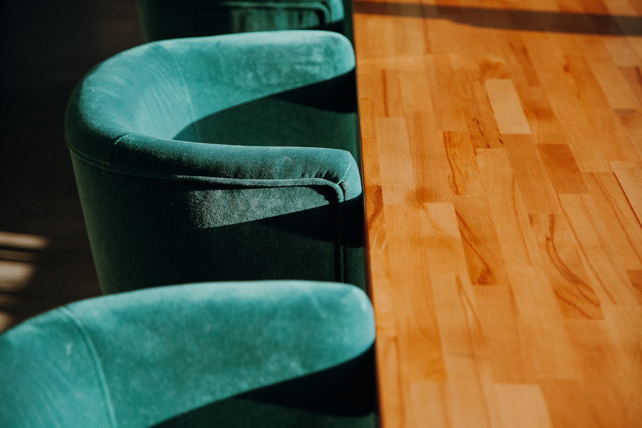 Close-up of stylish green chairs and a wooden table in warm lighting.